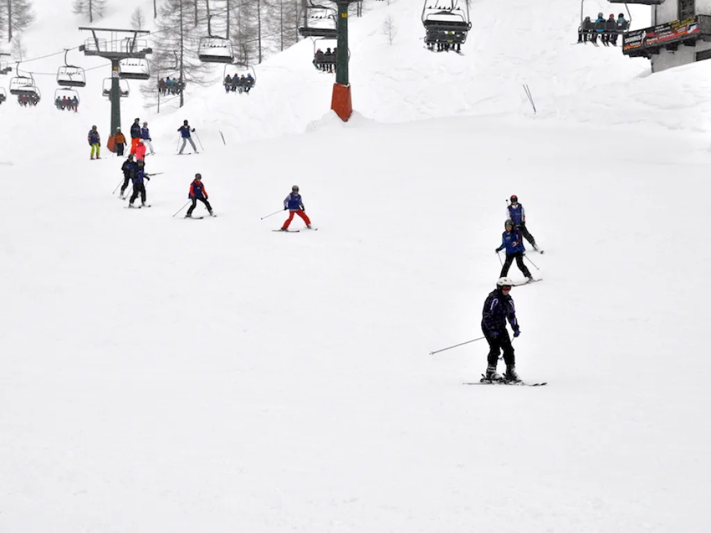 Skifahrende auf der Piste unter dem Sessellift.